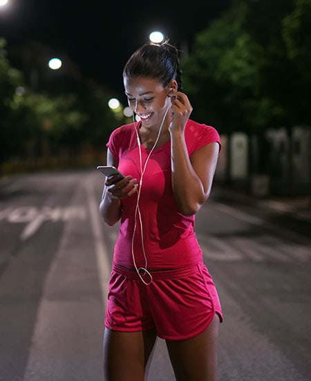Woman in bright pink running gear looking at phone